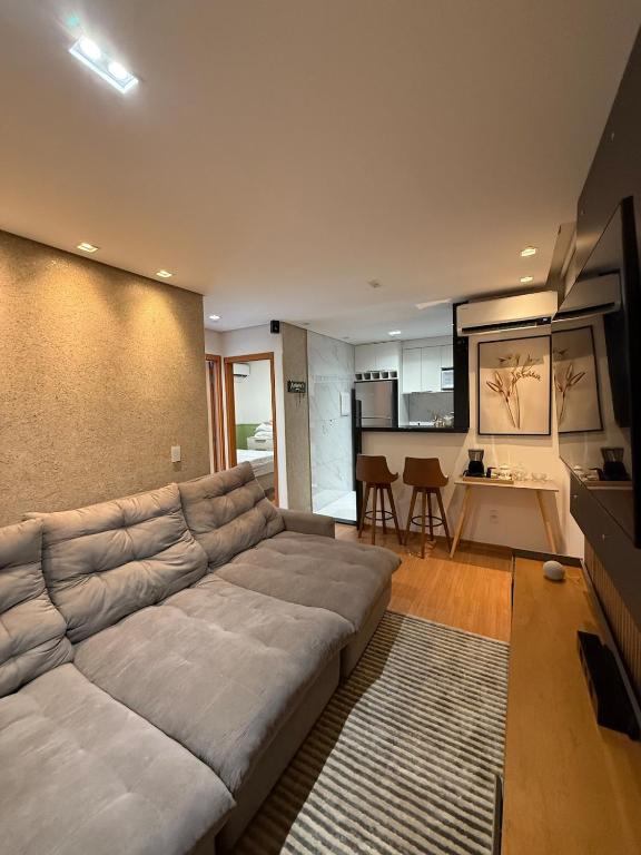 a living room with a large couch and a kitchen at Belo Apartamento Com Piscina in Várzea Grande