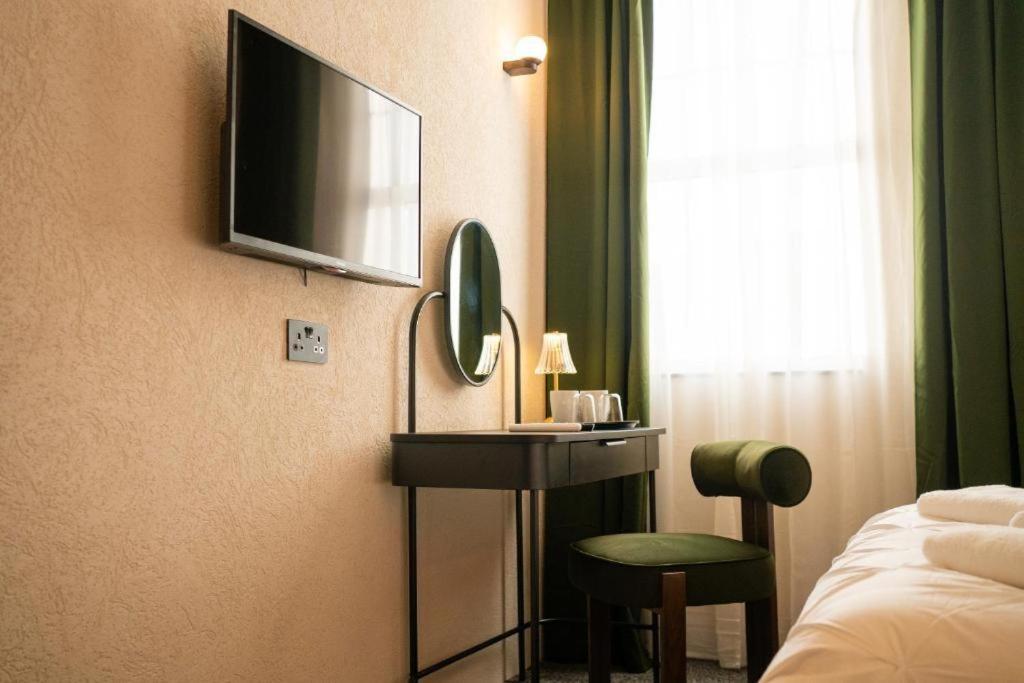 a hotel room with a television and a table and a bed at Roza Hotel in Enfield