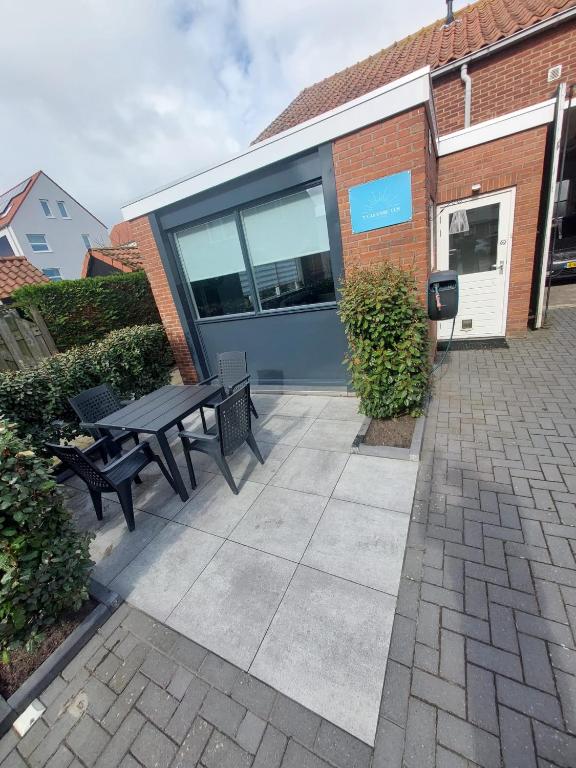 a patio with a table and benches in front of a building at 't Vakansie'uus in Serooskerke