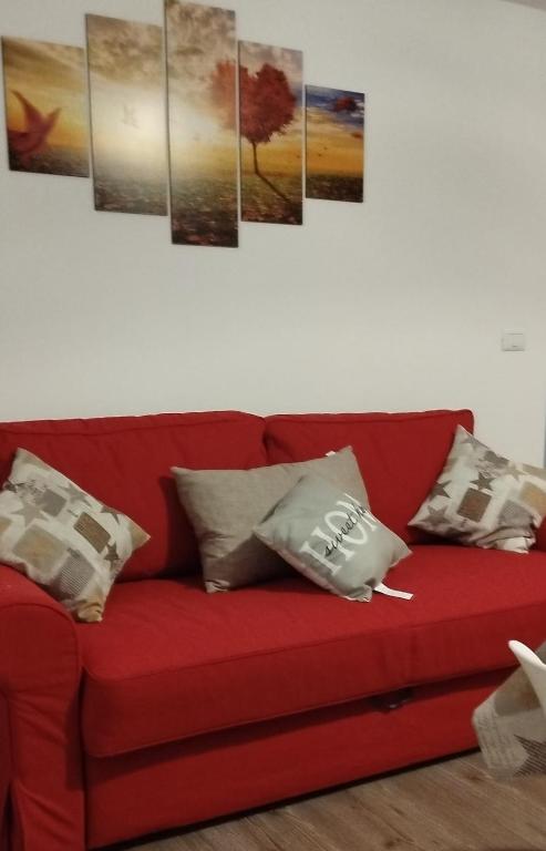 a red couch with four paintings on the wall at S1 Home Sila in Camigliatello Silano