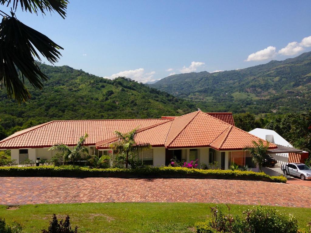 una casa con techo rojo con montañas al fondo en Casa Campestre Condominio Bellavista, en Tobia