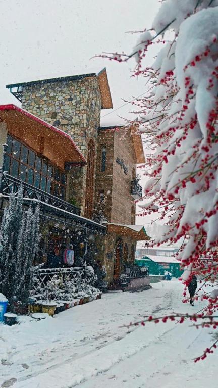a building with snow on the branches of a tree at Hotel Alpine Musk in Kanatal