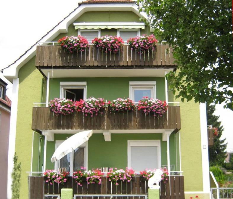 a green house with a balcony with flowers on it at Ferienwohnung Zentral in Langenargen