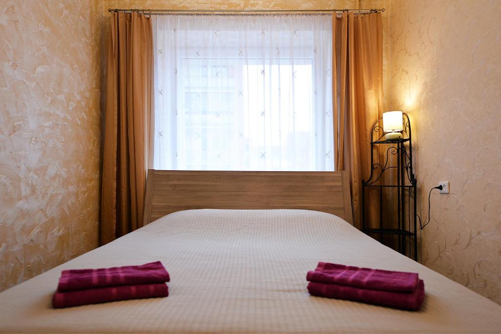 2 almohadas moradas en una cama frente a una ventana en Central Apartments Karolina en Druskininkai