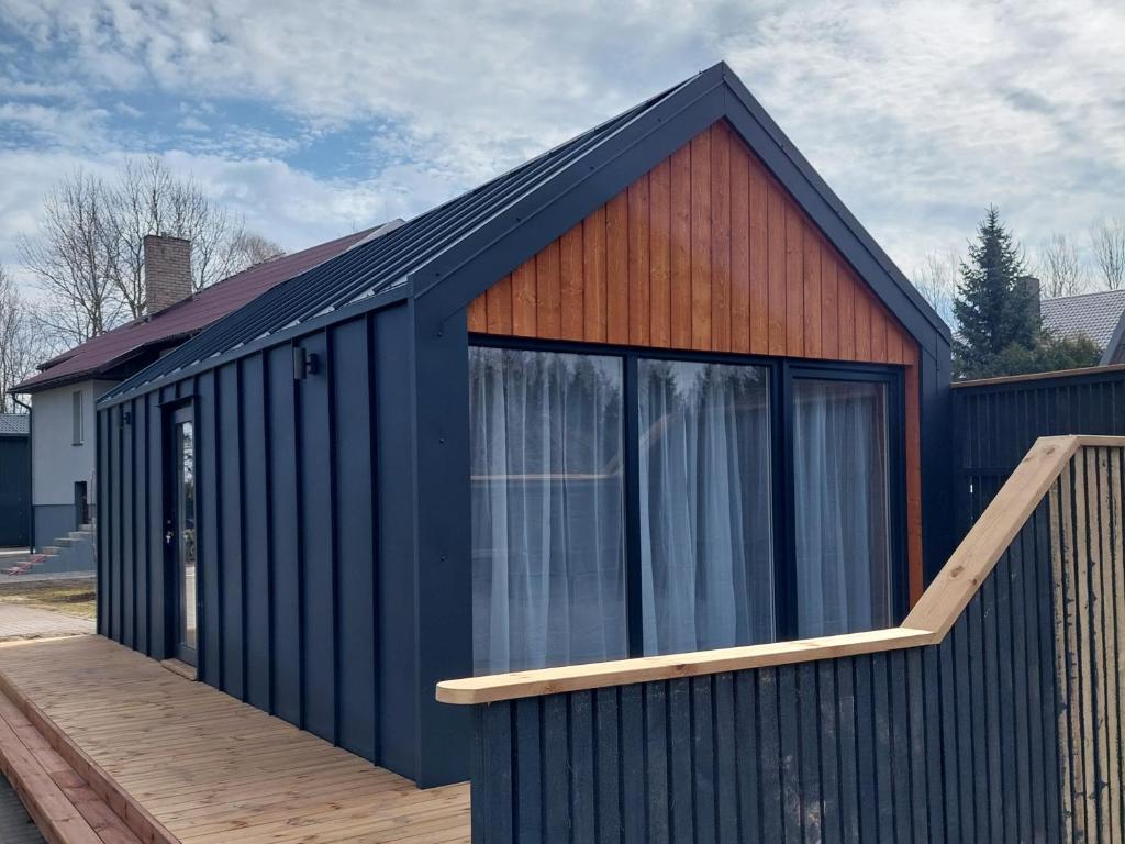 a large blue building with a wooden deck at Trijų namelių uostas in Dreverna