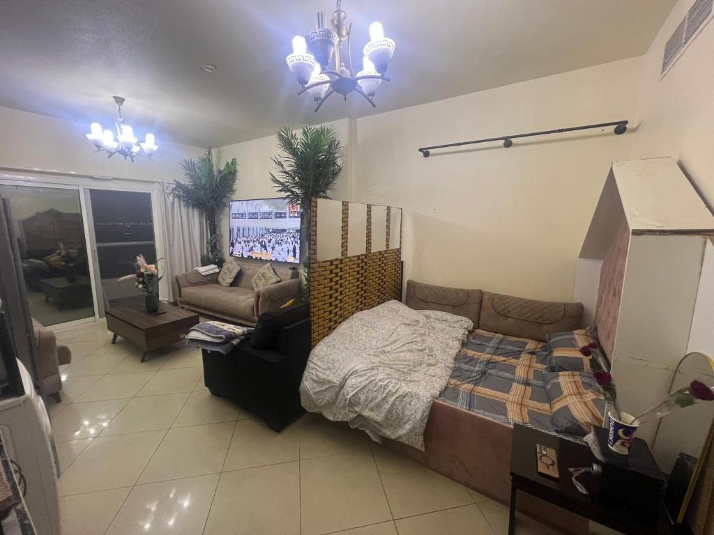 a bedroom with a bed and a couch and a chandelier at Sahara View Guest House Prime Location on the Dubai Sharjah Border in Sharjah