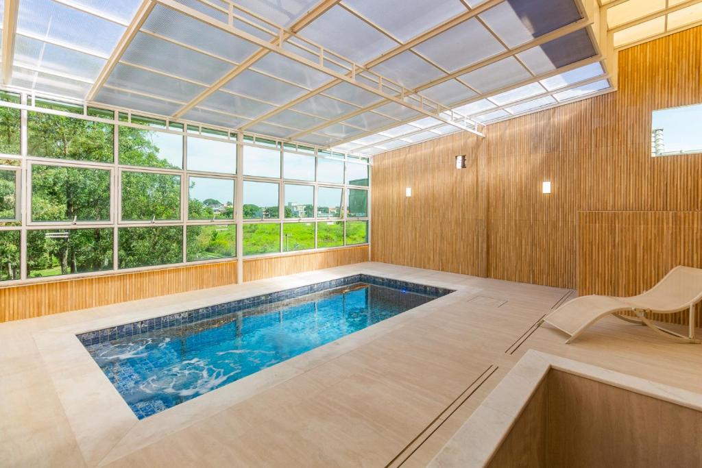 a swimming pool in a room with a large window at Hotel Morada Del Este in Canoas