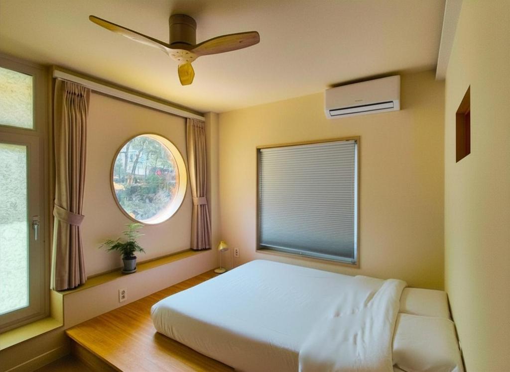 a bedroom with a bed and a window with a fan at SoSi Stay in Seoul