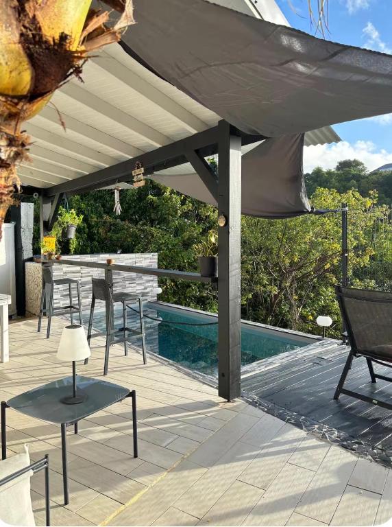 a patio with a table and chairs and a pool at Blue dream Bungalow in Le Gosier