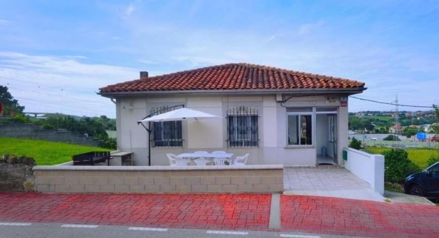 a small white house with a table and an umbrella at Villa Mayki in Cacicedo