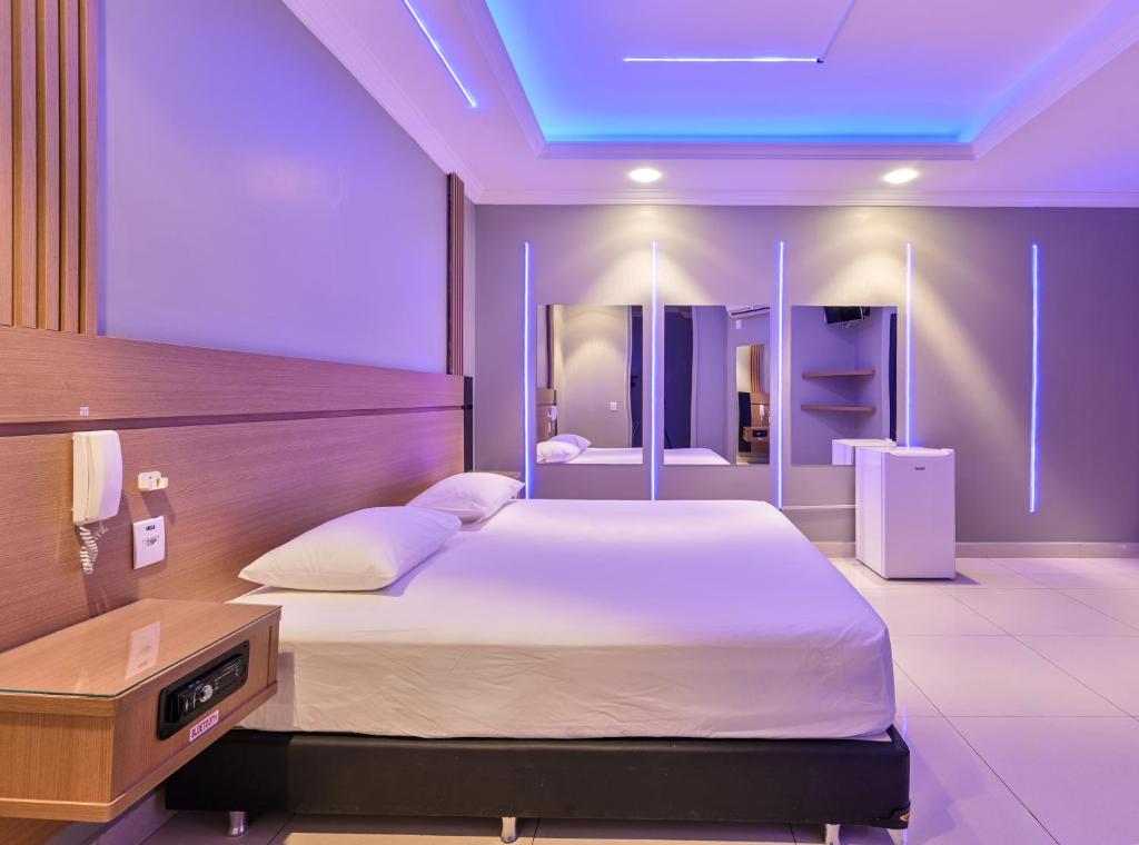 a bedroom with a large bed with a blue ceiling at Drops Motel Araraquara in Araraquara