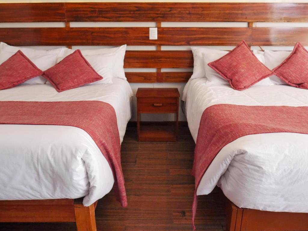 a bedroom with two beds with red and white pillows at Casona Urinsaya Qolca in Chivay