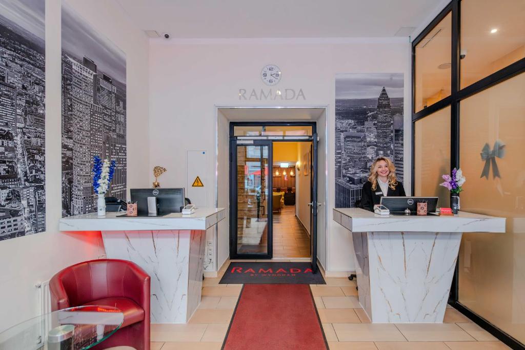 a woman sitting at a counter in a coffee shop at Ramada by Wyndham Frankfurt Central Station in Frankfurt