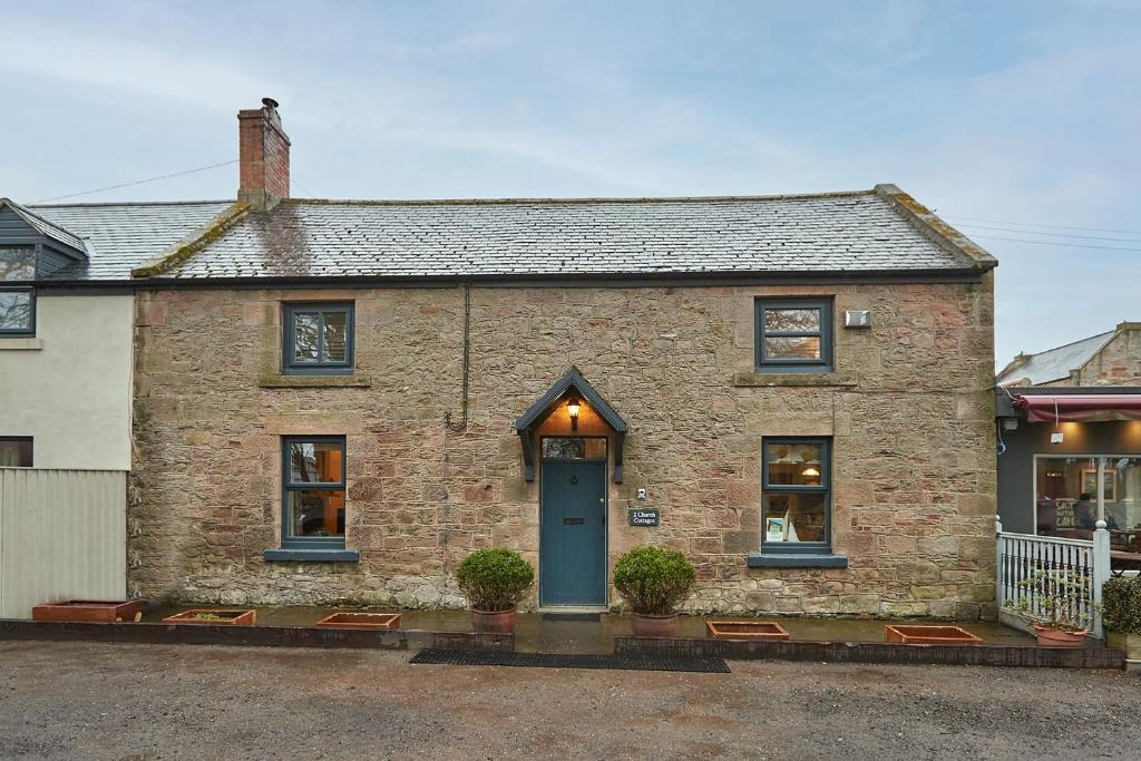 an old brick house with a blue door at Church Cottage by Coast & Country Stays in Beadnell