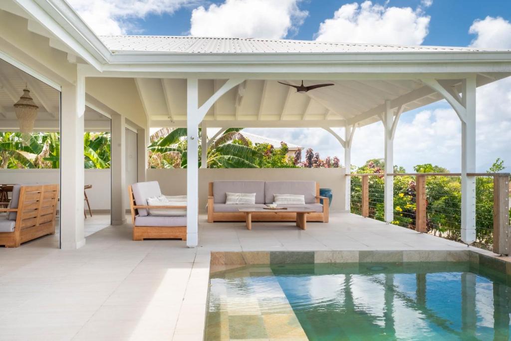 an outdoor patio with a pool and a pergola at Villa Joséphine in Grand-Bourg