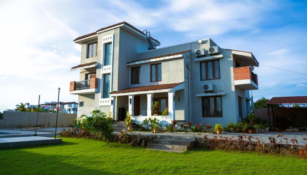 a blue and white house with a yard at VILLA De OMR, Private Pool Villa at Old Mahabalipuram Road, Chennai in Kelambākkam
