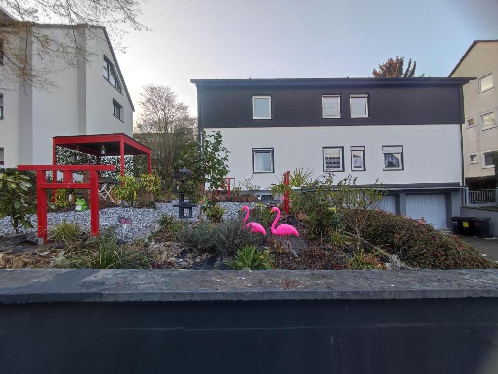 two pink flamingos in a garden in front of a building at Uni nähe Unterkunft mit Garten in Bochum