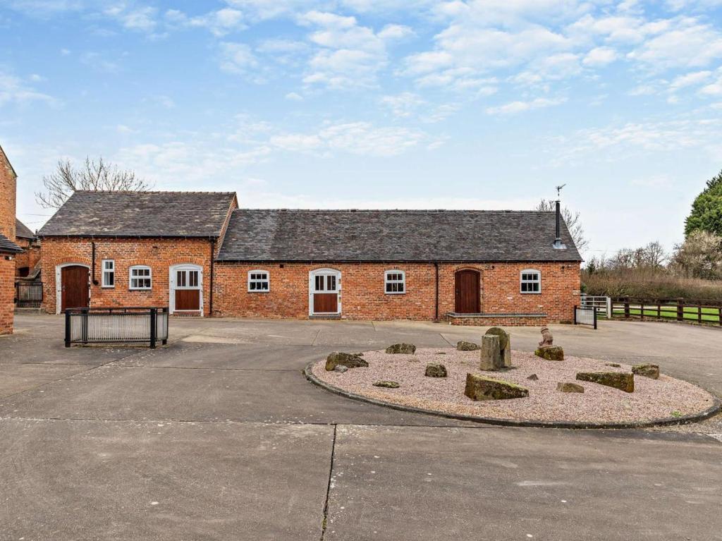 a red brick building with a stone circle in front of it at 3 Bed in Ashbourne oc-94309 in Windley