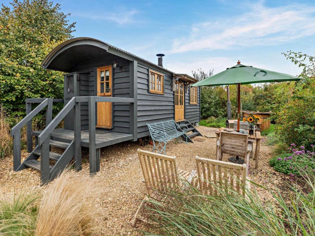 a gray tiny house with a table and an umbrella at 1 Bed in Lutterworth oc-93760 in Boughton