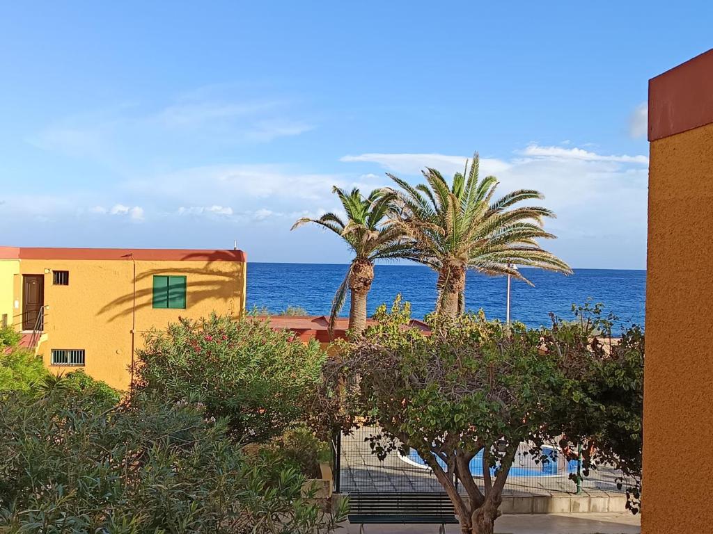 two palm trees and a building and the ocean at casa agua y sol 2 in Poris de Abona