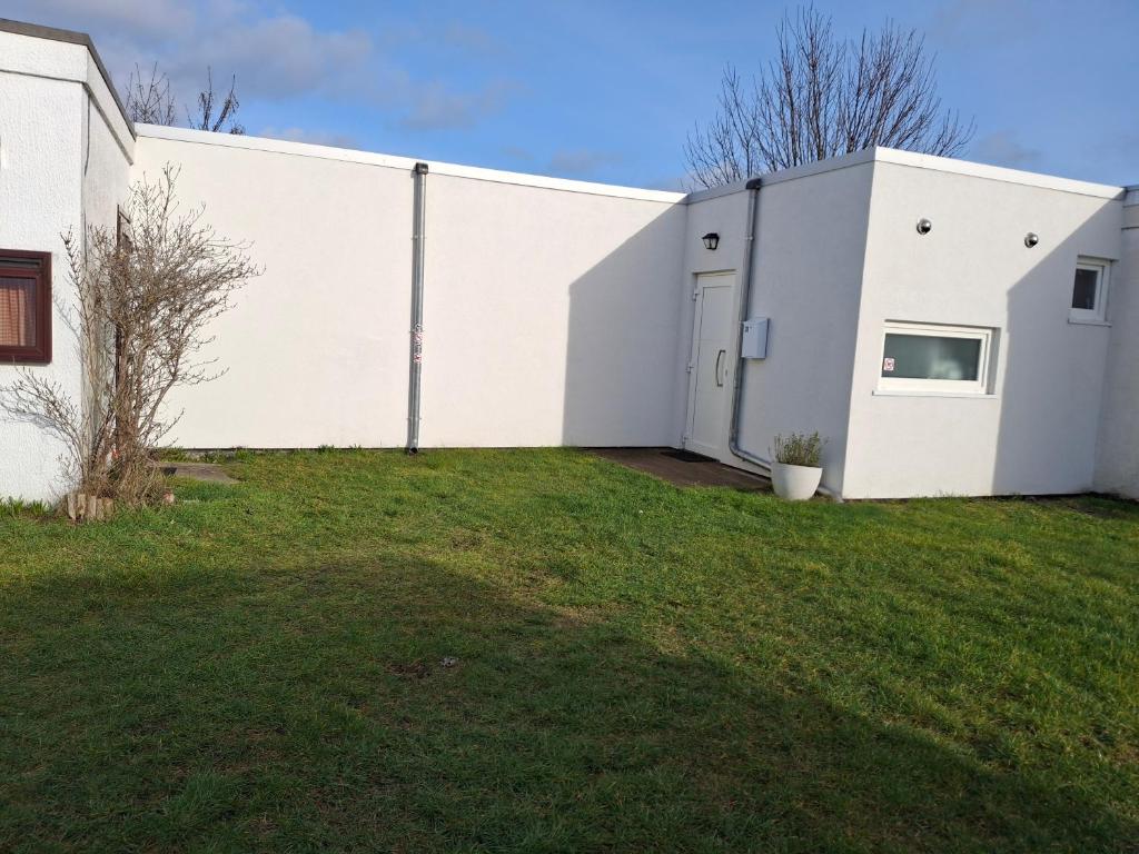 a white building with a grass yard at Maison de vacances Etoile de mer 2 in Koksijde