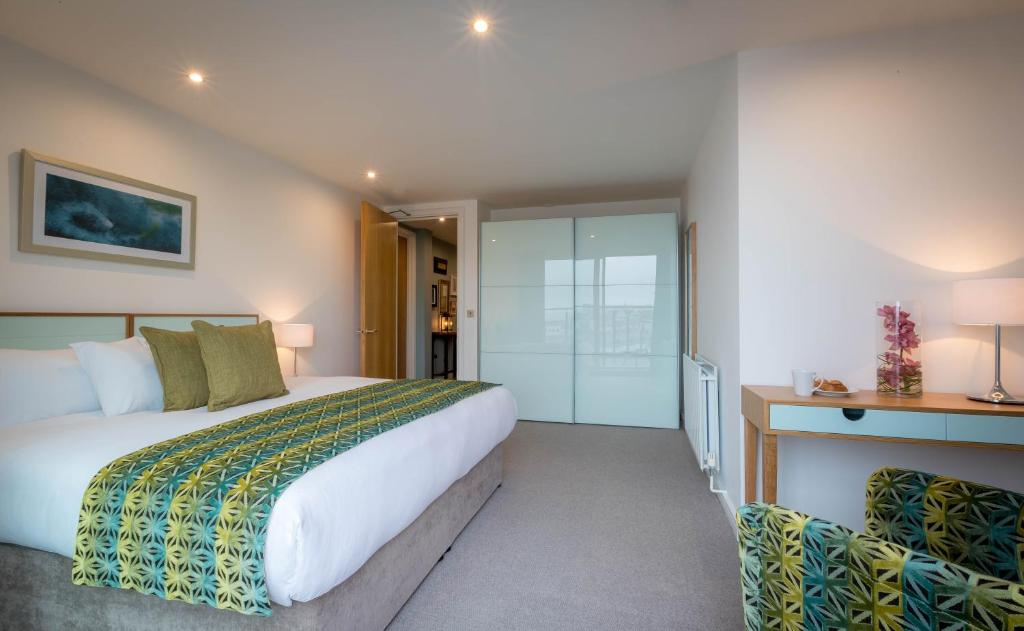 a bedroom with a large white bed and a desk at Talbot Suites at Stonebridge in Wexford