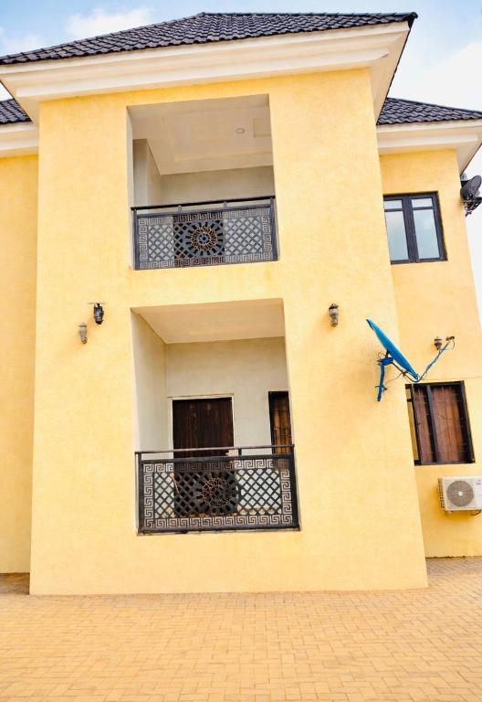 a yellow building with a balcony and a blue bird on it at Prime Ville in Rubuchi