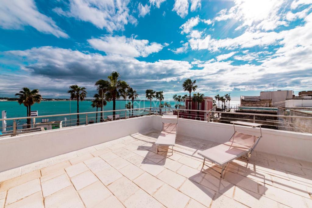 a balcony with two chairs and a view of the water at DIO DEL MARE LUXURY ROOM in Porto Cesareo