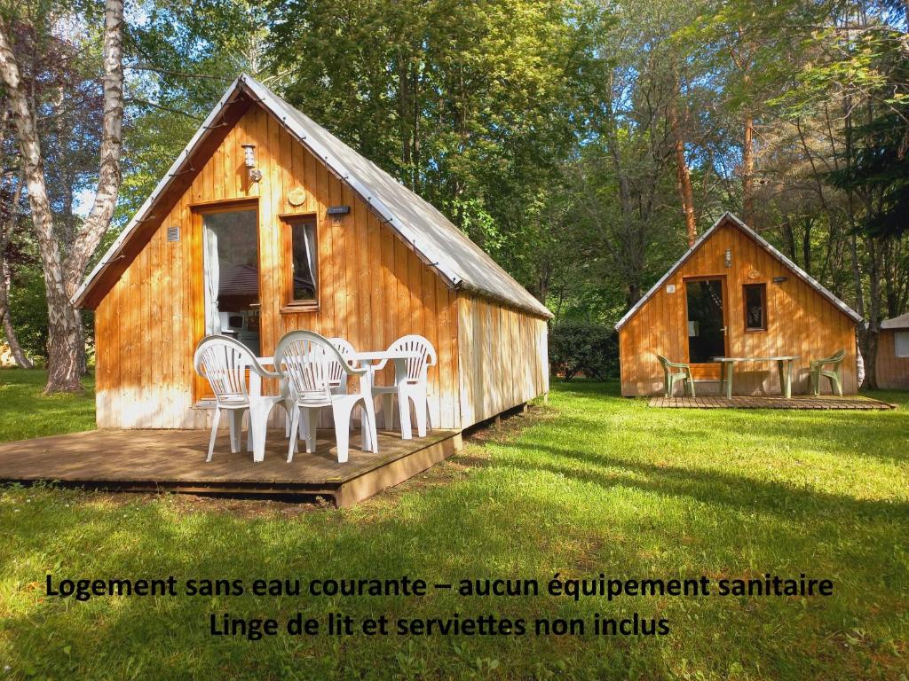 a wooden cabin with chairs and a table in the yard at TRAPPEUR - Les Chalets du lac Belcaire in Belcaire