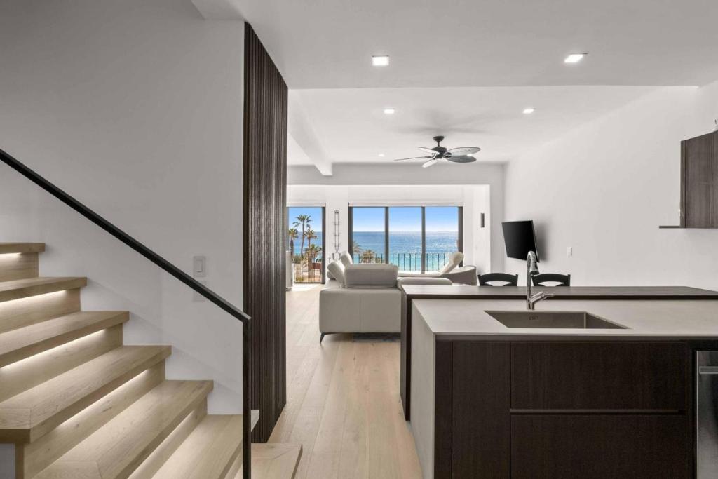 a kitchen and living room with a staircase and a couch at Elegant Beachfront Penthouse | Casa Del Mar Delfin in San José del Cabo