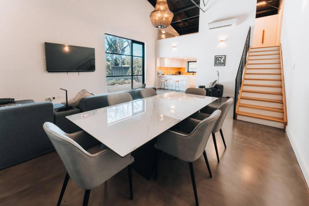 a dining room with a large white table and chairs at Daybreak Loft. Willunga in Willunga