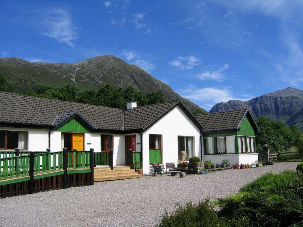 a house with mountains in the background at Hawthorn in Glencoe