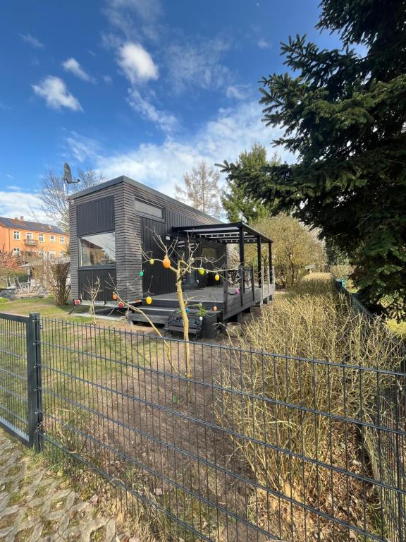 a tiny house is shown behind a fence at Tiny House Spreemaus in Hangelsberg