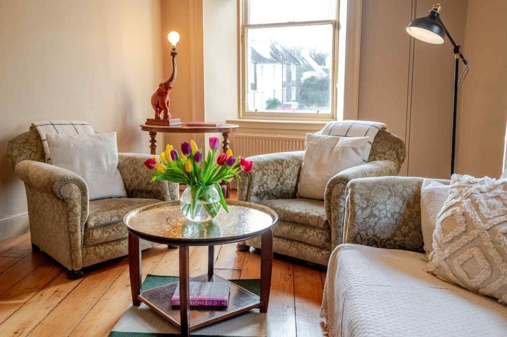 a living room with two couches and a table with flowers at Mackenzie House in Kirkcudbright