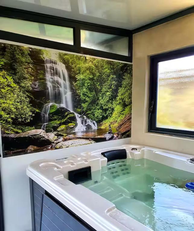 a bath tub with a waterfall painting on the wall at les gites du verger in Recey-sur-Ource