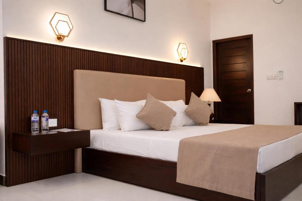 a bedroom with a large bed with a wooden headboard at Yaazoraa Anuradhapura in Maha Kalattewa