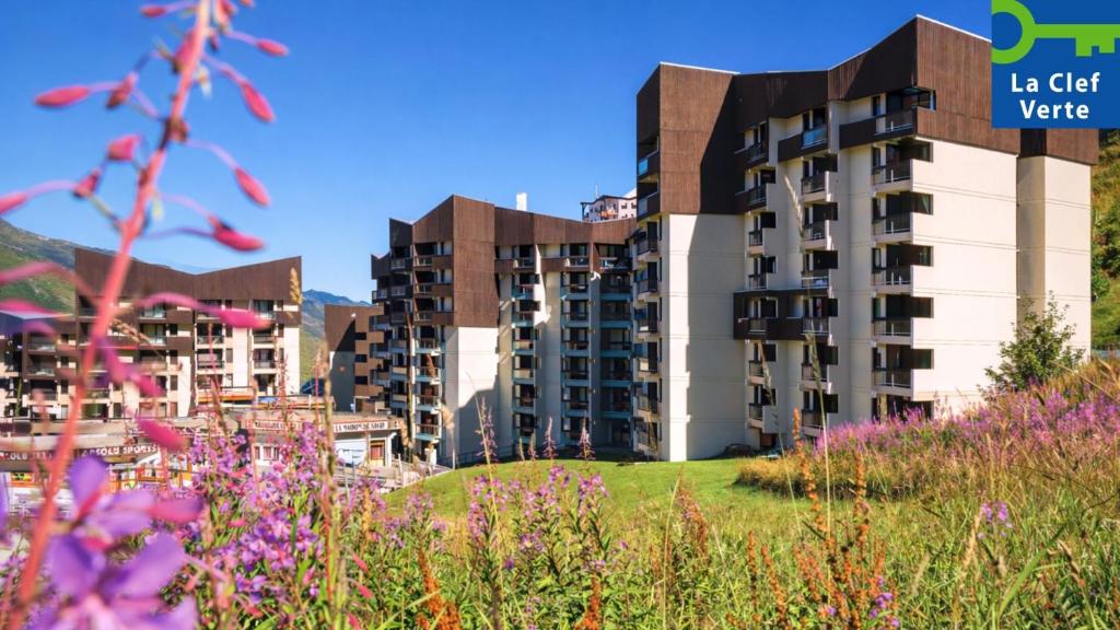 a view of a building with flowers in the foreground at Résidence Pierre & Vacances Les Combes in Les Menuires