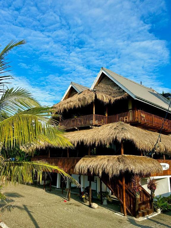 a building with a straw roof and a palm tree at surf dom hotel & restaurants in Ahangama