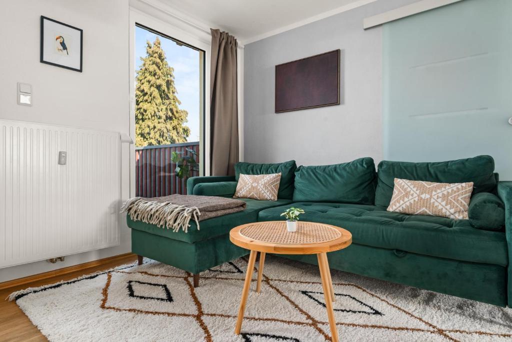 a living room with a green couch and a table at Tucan - Rooftop Terrace with View, BBQ, PS4+Stream in Marburg an der Lahn