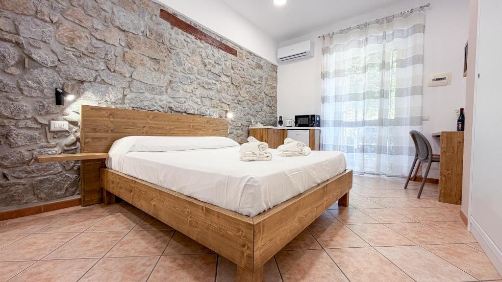 a bedroom with a bed and a stone wall at Hortensia House in Cefalù