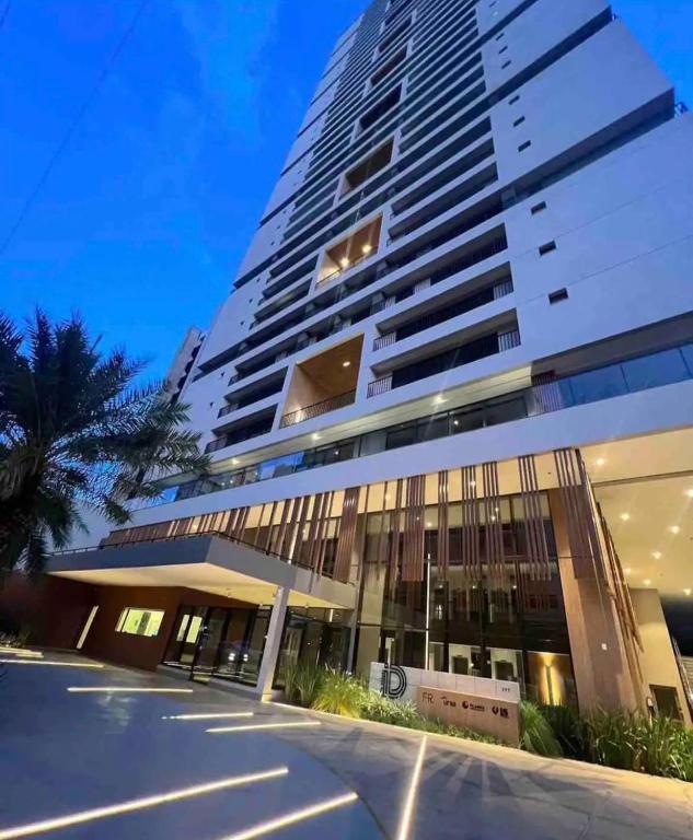a tall building with a palm tree in front of it at Royal ID Setor Oeste in Goiânia