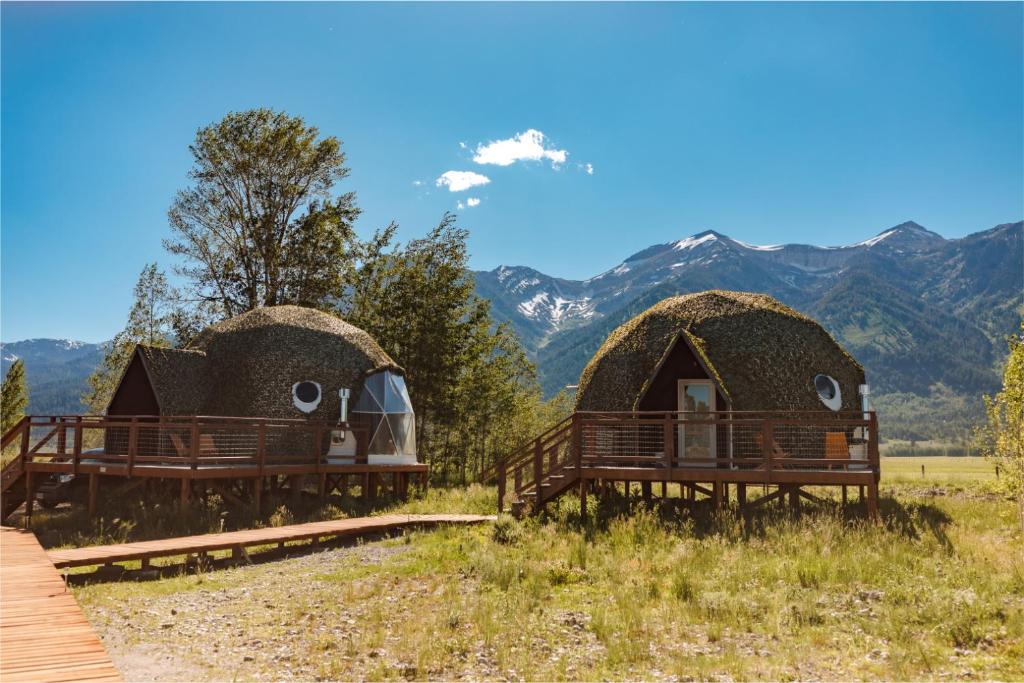 two thatched cottages with mountains in the background at Tammah Jackson Hole in Wilson