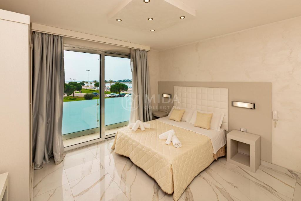 a bedroom with a bed and a large window at Riviera Luxury Rooms in Porto Cesareo