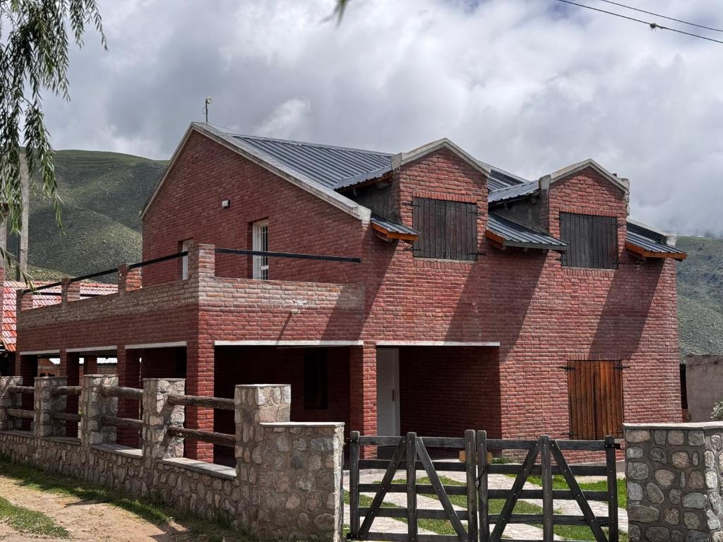 a red brick house with a fence in front of it at Casa Bati in El Mollar