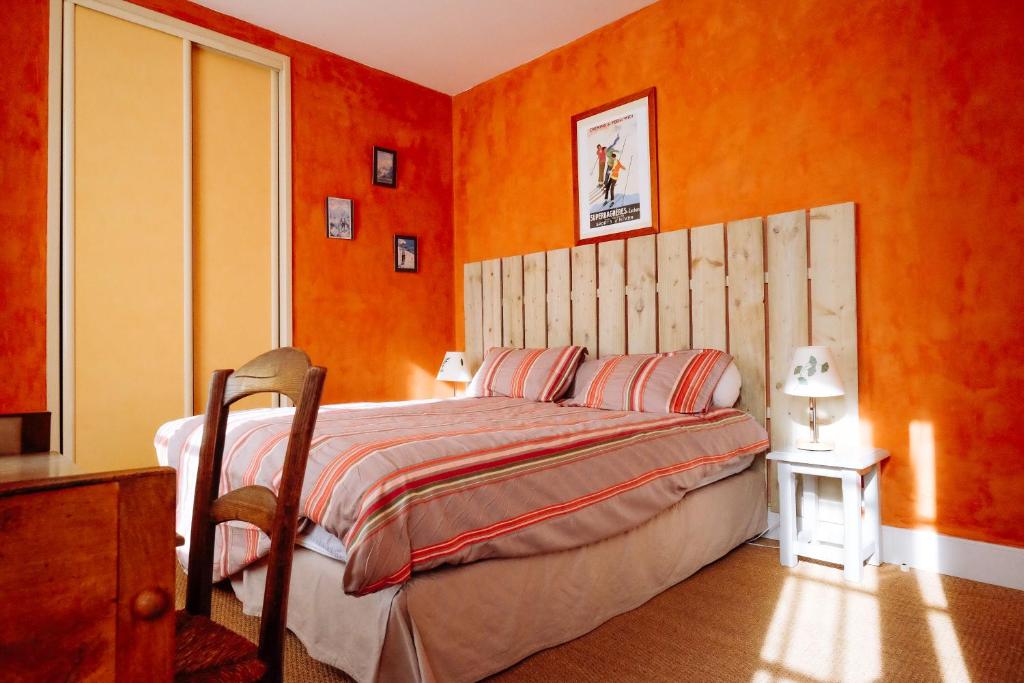 Le Poujastou في Juzet-de-Luchon: غرفة نوم مع جدران برتقالية وسرير مع اللوح الأمامي الخشبي