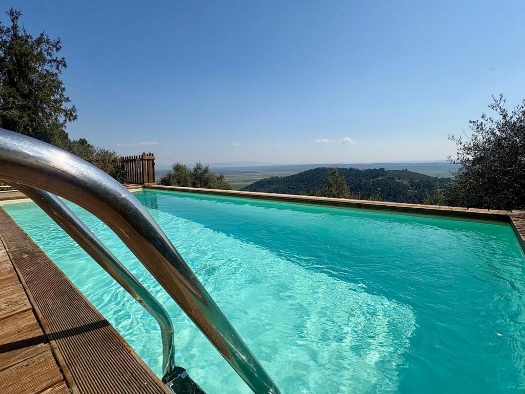 ein großer blauer Swimmingpool mit einer Holzbank daneben in der Unterkunft Rivolta home in Buti