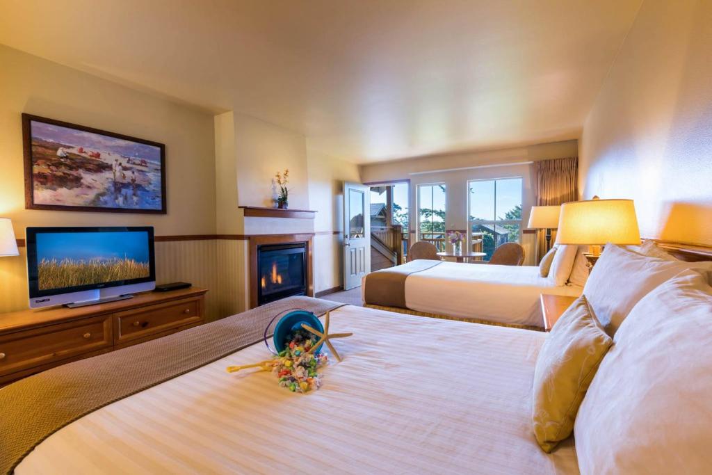 a hotel room with two beds and a fireplace at Inn at Cannon Beach in Cannon Beach
