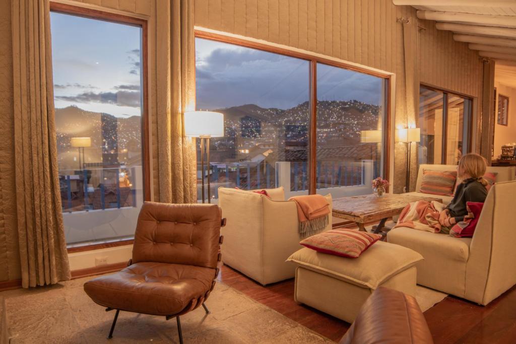 a woman sitting in a living room with a large window at Tocuyeros Boutique Hotel in Cusco