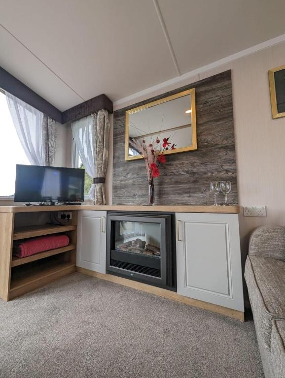 a living room with a fireplace and a tv at Swift Bordaux 68 in Ardentinny