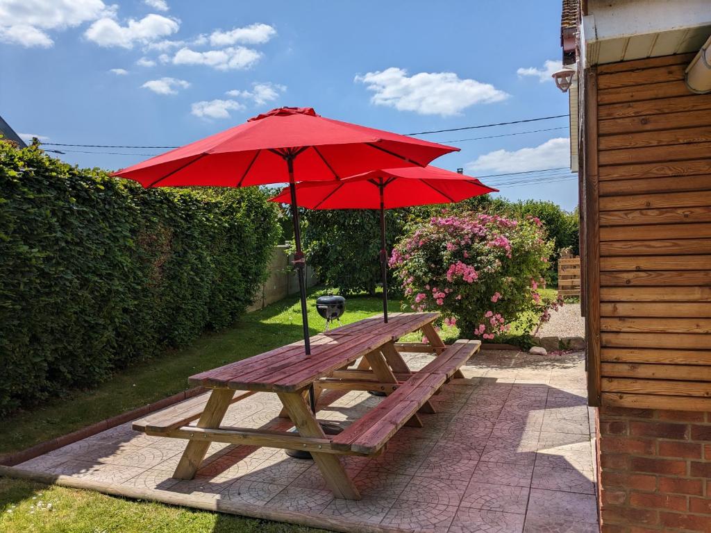 a wooden picnic table with a red umbrella at Le temps des vacances in Vaudricourt
